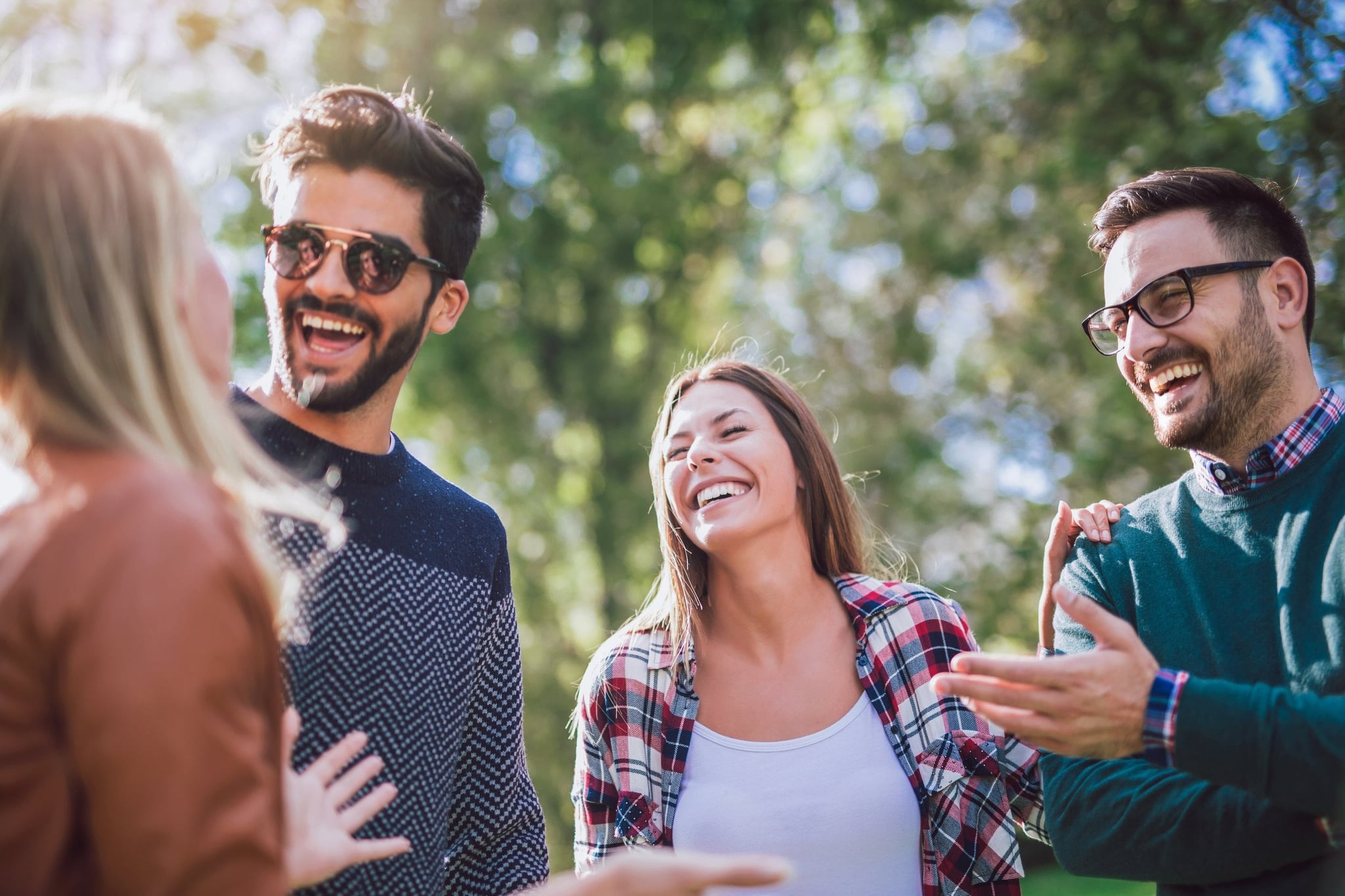 Group of four friends smiling and talking outdoors in a park